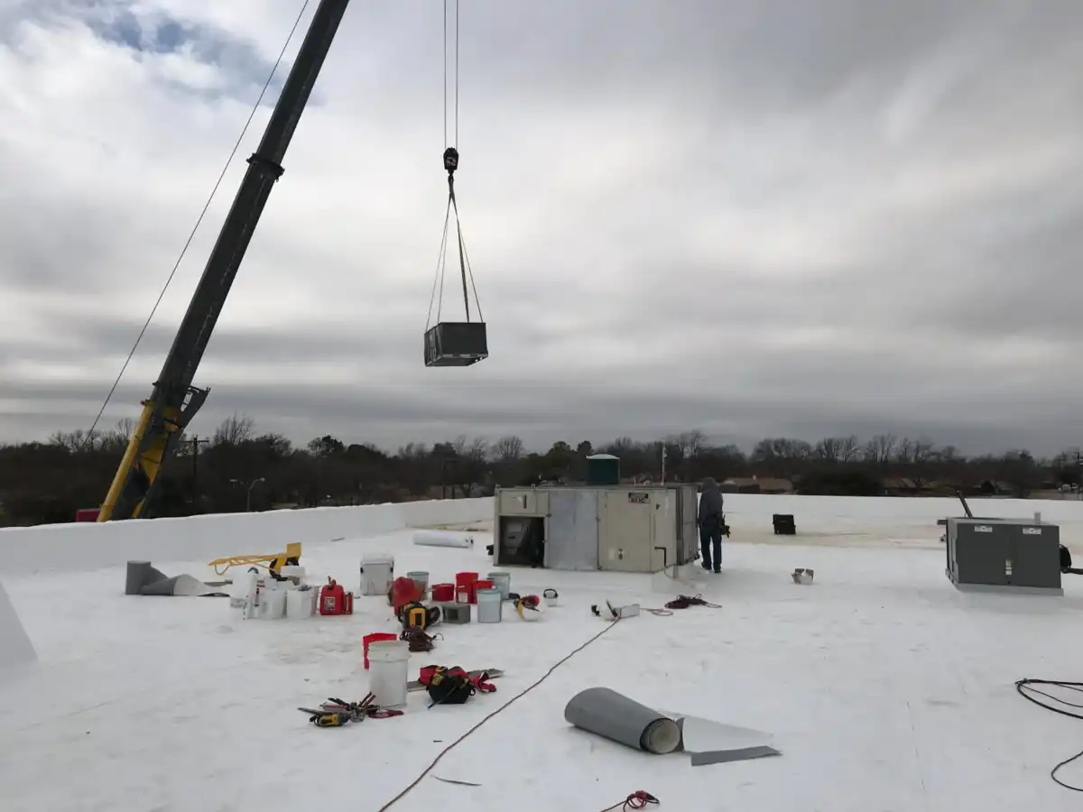 Crane lifting HVAC unit onto commercial TPO roof